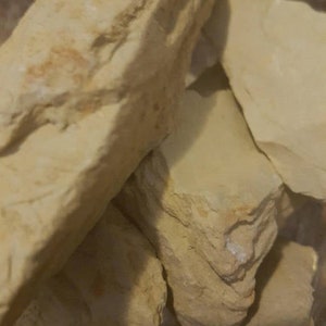 May include: Close-up of a pile of light beige clay, showing its rough, textured surface.