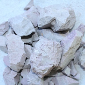 May include: A pile of light gray and purple clay rocks. The rocks are irregular in shape and have a rough texture.