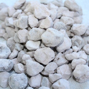 May include: A pile of small, light gray, irregularly shaped rocks. The rocks have a rough, porous texture.