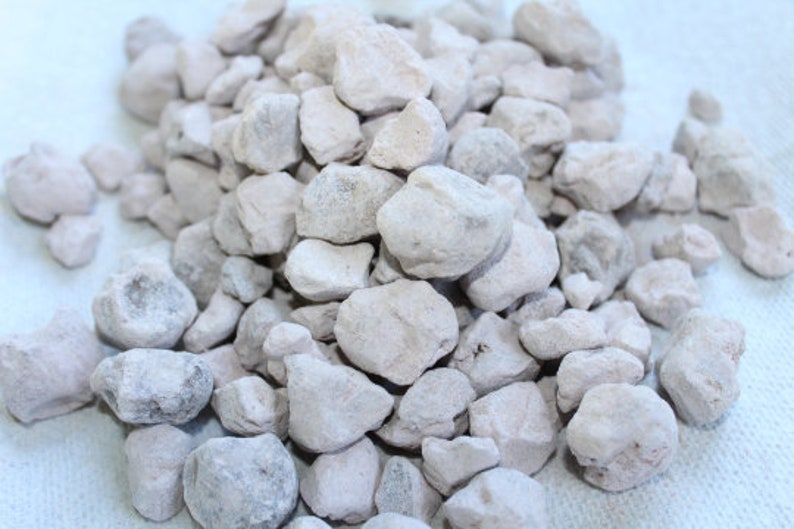 Puede incluir: Un mont&oacute;n de peque&ntilde;as piedras de color gris claro, de forma irregular. Las piedras tienen una textura rugosa y porosa.