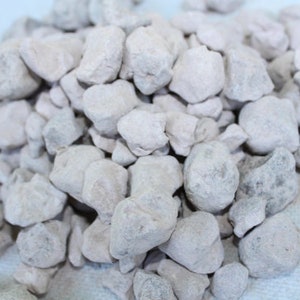 Puede incluir: Un mont&oacute;n de peque&ntilde;as piedras blancas de forma irregular. Las piedras son lisas y tienen una textura ligeramente rugosa.