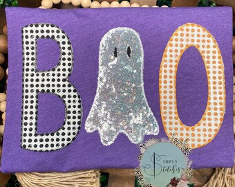 May include: Purple shirt with a black and white polka dot "B", a silver sequin ghost, and an orange polka dot "O" that reads "BOO".