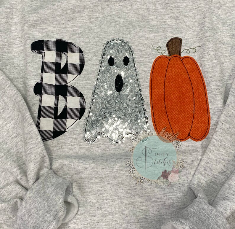 May include: A gray sweatshirt with a black and white checkered "B", a silver sequined ghost, and an orange pumpkin with a green stem that says "BOO" on it.