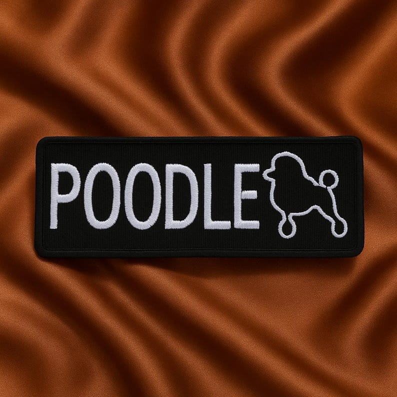 May include: A black rectangular patch featuring the word "POODLE" in white embroidery, and a white poodle outline. The patch is displayed against a brown, textured backdrop.