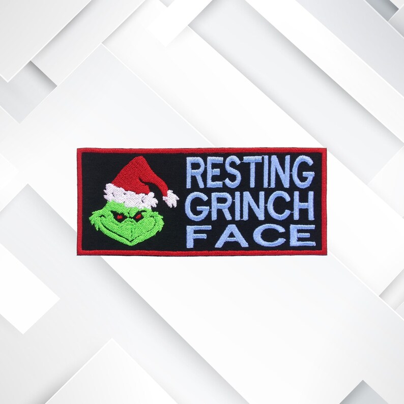 May include: Embroidered patch featuring the Grinch wearing a Santa hat. The patch has a black background with the words "RESTING GRINCH FACE" in light blue. The Grinch is green with a red and white Santa hat.
