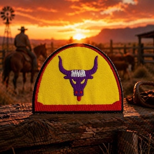May include: A yellow, semi-circular patch with a purple bull head design. The bull has large horns and a red tongue. The patch is bordered by a red and black trim. The background features a sunset, a cowboy on a horse, and a windmill.