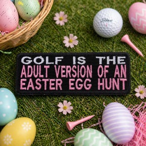 May include: A black patch with white and pink text that reads "GOLF IS THE ADULT VERSION OF AN EASTER EGG HUNT" is surrounded by Easter eggs, golf balls, and pink golf tees on a bed of green grass. A wicker basket holds more Easter eggs.