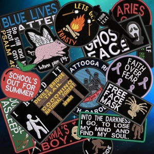 May include: A selection of embroidered patches featuring diverse designs and text. Patches include a winged pig, a campfire with marshmallows, a ghost face, an apple, and phrases such as "School's Out For Summer" and "Free Face Mask".