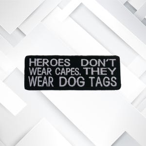 Può includere: Toppa ricamata nera con testo bianco che recita "HEROES DON'T WEAR CAPES, THEY WEAR DOG TAGS".