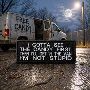 Puede incluir: Un parche en blanco y negro con el texto "I GOTTA SEE THE CANDY FIRST THEN I'LL GET IN THE VAN I'M NOT STUPID" está delante de una furgoneta blanca con "FREE CANDY" escrito en el lateral. La puerta de la furgoneta está abierta.
