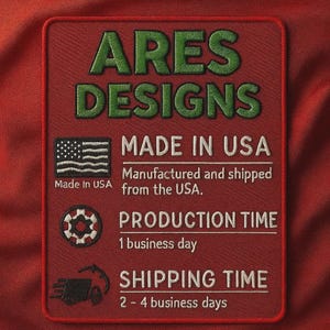 Op de afbeelding: Een rood geborduurd embleem met de tekst "ARES DESIGNS" in groen. Daaronder staat "MADE IN USA" met een Amerikaanse vlag. Het embleem vermeldt ook "PRODUCTION TIME 1 werkdag."