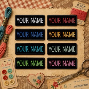 May include: A collection of eight rectangular black embroidered patches, each with the words "YOUR NAME" in a different color. The patches are arranged on a textured surface with sewing supplies, including thread spools, buttons, and scissors.