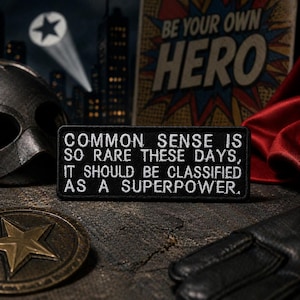 以下が含まれることがあります： 白い刺繍のテキストが入った黒い長方形のパッチ：「COMMON SENSE IS SO RARE THESE DAYS, IT SHOULD BE CLASSIFIED AS A SUPERPOWER。」マスク、シールド、そして「BE YOUR OWN HERO」という言葉を使ったスーパーヒーローのテーマ。