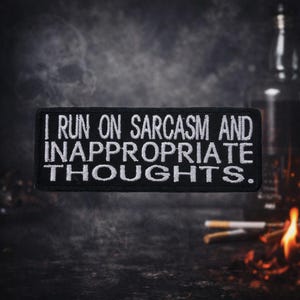 May include: Black rectangular patch with white embroidered text that reads "I RUN ON SARCASM AND INAPPROPRIATE THOUGHTS." The patch is set against a dark, blurred background with hints of fire and cigarettes.