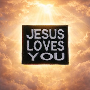 May include: A black square patch with the embroidered text "JESUS LOVES YOU" in white. The patch is set against a background of a bright, sunlit sky with fluffy clouds.