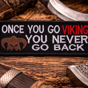 May include: Black rectangular patch with white text that reads "ONCE YOU GO VIKING YOU NEVER GO BACK." The word "VIKING" is in red. A brown horned helmet graphic is on the left. The patch is surrounded by a black border.