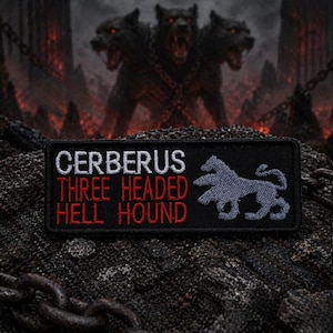 May include: Black patch with the words "CERBERUS THREE HEADED HELL HOUND" in white and red lettering. A gray silhouette of a dog is on the right. The background features a three-headed dog and a fiery landscape.
