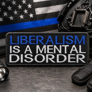 May include: A black patch with the words "LIBERALISM IS A MENTAL DISORDER" in white and blue lettering. The patch is surrounded by a black border. The background includes a black and white American flag with a blue stripe, a tactical helmet, a flashlight, and gloves.