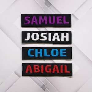 May include: Four black fabric patches with white stitching, each with a different name embroidered in a different color: Samuel in purple, Josiah in white, Chloe in blue, and Abigail in red.