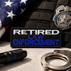 May include: A black patch with white embroidered text reading "RETIRED LAW ENFORCEMENT" and a blue stripe. An American flag, a badge, a flashlight, and handcuffs are also visible. The badge reads "SERVICE INTEGRITY".