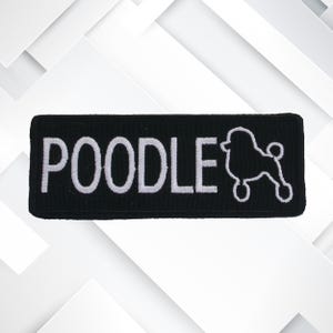 May include: A black rectangular patch featuring the word "POODLE" in white embroidery, accompanied by a white poodle outline. The patch has a black border and is designed for application to fabric.