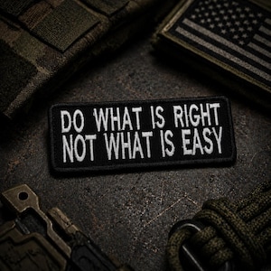 Puede incluir: Parche rectangular negro con texto blanco bordado: "DO WHAT IS RIGHT NOT WHAT IS EASY". El parche está rodeado de equipo de estilo militar y un parche de la bandera estadounidense.