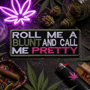 May include: A black patch with the text "ROLL ME A BLUNT AND CALL ME PRETTY" in white, green, and pink. The patch is surrounded by cannabis leaves, a neon cannabis leaf, and a lighter with a cannabis leaf.