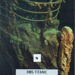 May include: An underwater image of the RMS Titanic wreckage, showing corroded metal and marine growth. A small coal relic is visible, along with a label stating "RMS Titanic Authentic Shipwreck Coal Relic."