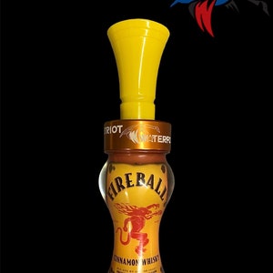 May include: Yellow duck call with a Fireball Cinnamon Whisky label. The label features a red dragon with flames and the text "Fireball Cinnamon Whisky".