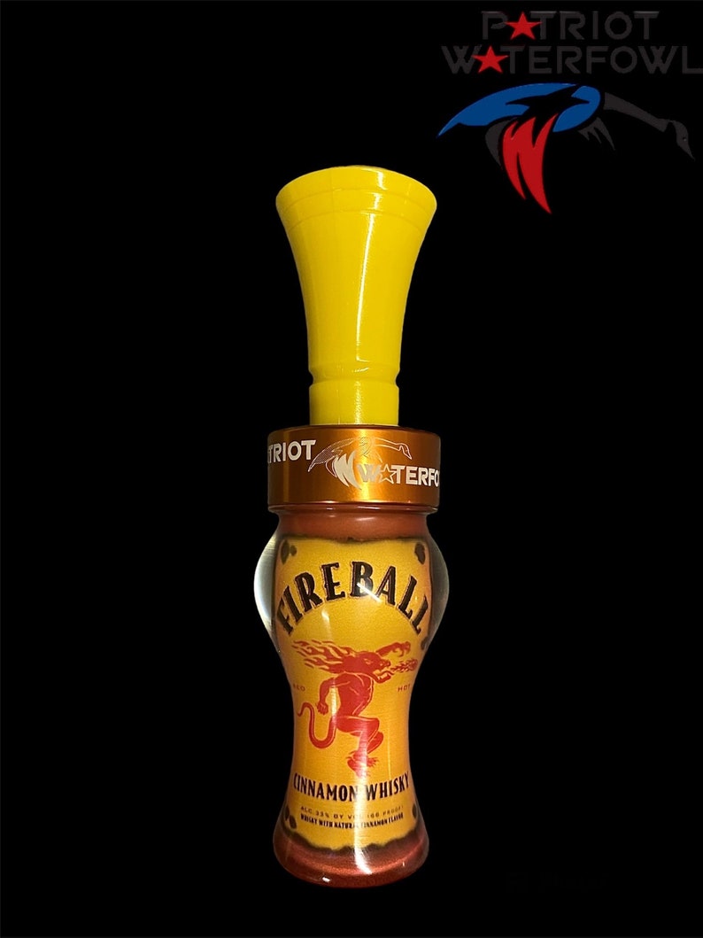 May include: Yellow duck call with a Fireball Cinnamon Whisky label. The label features a red dragon with flames and the text "Fireball Cinnamon Whisky".
