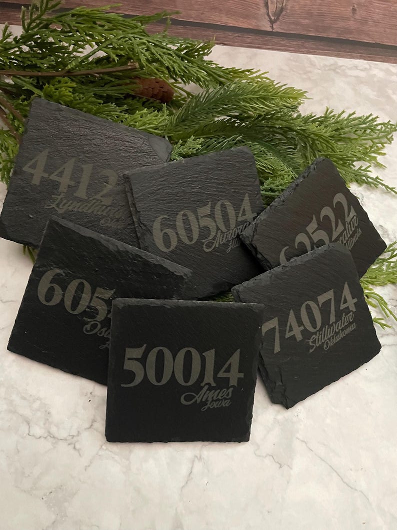 Puede incluir: Seis posavasos de pizarra negra con n&uacute;meros y nombres de ciudades grabados en blanco. Los posavasos presentan los n&uacute;meros 4412, 60504, 62522, 605, 50014 y 74074. Los nombres de las ciudades son Lyndhurst, Aurora, Palatine, Osage, Ames y Stillwater.