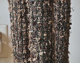 May include: Four brown cylindrical moss poles with a green wire mesh covering. The poles are stacked on top of each other.