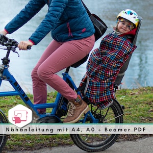 Könnte beinhalten: Eine Frau fährt ein blaues Fahrrad mit einem Kind in einem karierten Sitz hinter sich. Das Kind trägt einen Helm und eine rote Jacke. Der Text "Nähnanleitung mit A4, A0 + Beamer PDF" befindet sich am unteren Rand des Bildes.