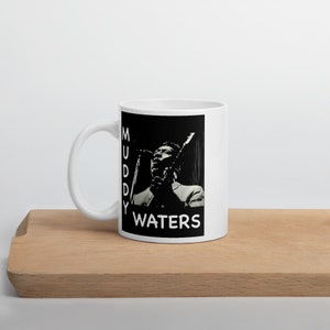 May include: White ceramic mug with a black and white image of Muddy Waters singing into a microphone. The text "MUDDY WATERS" is printed in white on the mug.
