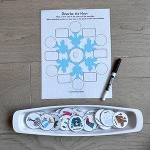May include: A snowflake-shaped game board with blank spaces around the center circle.  There are 15 small round cards with various winter-themed images and words, such as "sweater", "boots", "snow", and "ornaments".