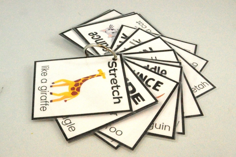 Peut inclure: Un jeu de cartes avec diff&eacute;rents mots et images, dont une girafe, un chat et le mot "stretch". Les cartes sont reli&eacute;es entre elles par un anneau m&eacute;tallique.