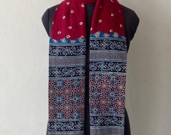 May include: A burgundy scarf with a patterned design. The scarf features a repeating white dot pattern on the top portion and a detailed floral and geometric pattern in navy blue and burgundy on the bottom. Burgundy tassels adorn the ends.