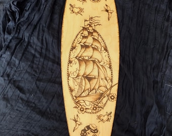 Hand burned traditional tattoo style shipwreck and pinup wood burning on birchwood surfboard, pyrography