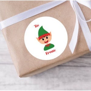 May include: A wrapped gift with a white ribbon and a round sticker featuring a cartoon elf. The sticker has the words "To:" and "From:" in red text. The gift is wrapped in brown paper.