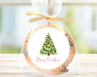 May include: A round white sticker with a watercolor illustration of a green Christmas tree with red and gold ornaments. The text "Merry Christmas" is written in red below the tree.