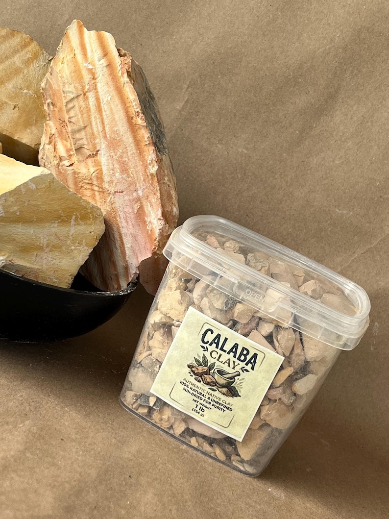 Puede incluir: Un recipiente de pl&aacute;stico transparente lleno de peque&ntilde;os trozos de arcilla de color tostado, etiquetado como Calaba Clay, 1 lb (454 g), junto a grandes rocas de arcilla cruda, estratificadas en tonos tostado y marr&oacute;n anaranjado.