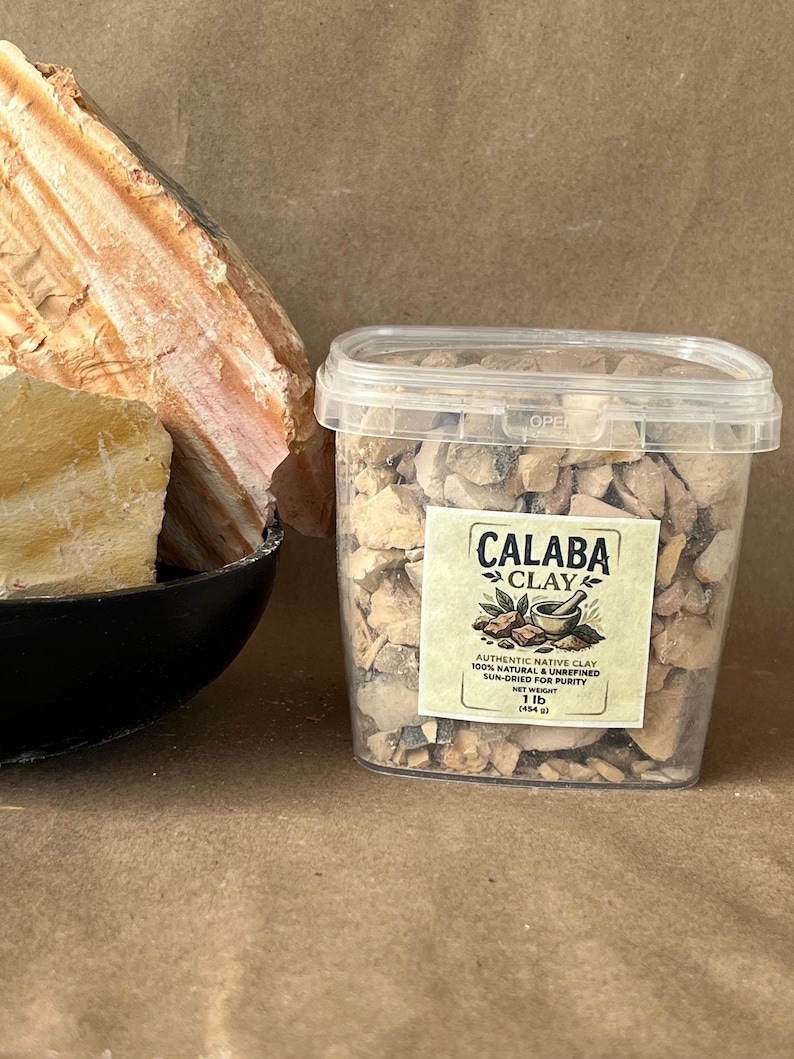 Puede incluir: Un recipiente de pl&aacute;stico transparente lleno de peque&ntilde;os trozos irregulares de arcilla Calaba de color tostado. La etiqueta dice Calaba Clay, Authentic Native Clay, 100% Natural & Unrefined, Sun-Dried for Purity, Net Weight 1 lb (454 g). Una roca grande y texturizada se encuentra al lado.