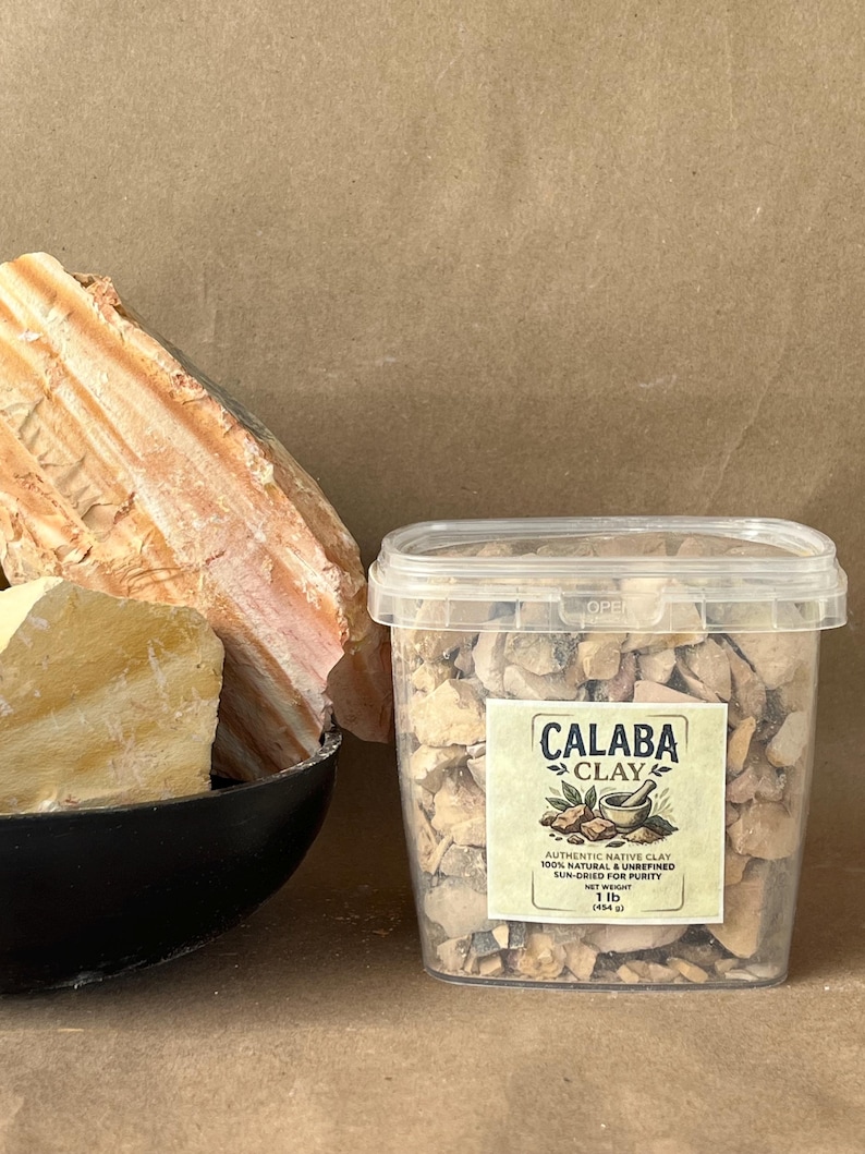 Puede incluir: Un recipiente de pl&aacute;stico transparente lleno de peque&ntilde;os trozos de arcilla Calaba de color tostado. La etiqueta dice: CALABA CLAY, AUTHENTIC NATIVE CLAY, 100% NATURAL & UNREFINED, SUN-DRIED FOR PURITY, NET WEIGHT 1 lb (454 g). Al lado hay un cuenco negro con grandes rocas de arcilla.