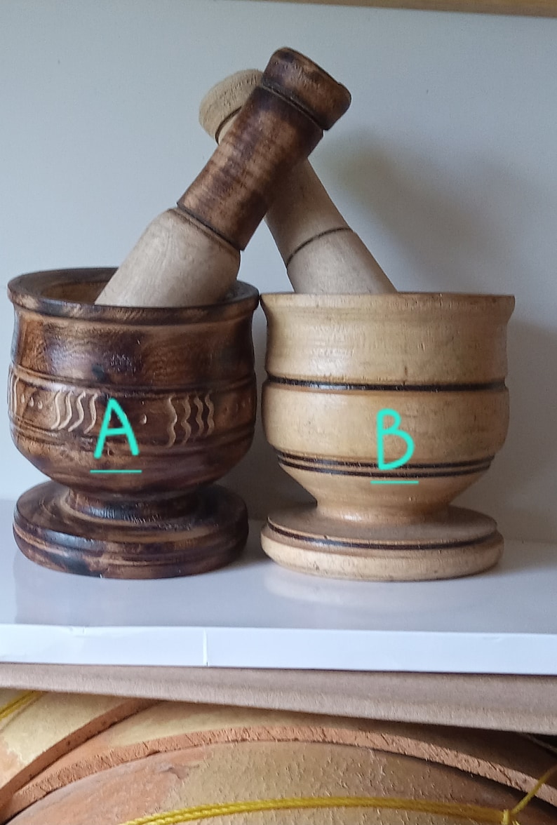 May include: Two wooden mortars and pestles, one with a dark brown finish and the other with a light brown finish. The dark brown mortar has a carved design and the light brown mortar has a simple design. Both mortars have a base and a pestle.
