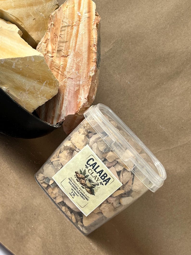 Puede incluir: Un recipiente de pl&aacute;stico transparente lleno de peque&ntilde;os trozos de arcilla de color beige, con una etiqueta que dice CALABA CLAY, 100% NATURAL & UNREFINED, SUN-DRIED FOR PURITY, 454 g. Al lado hay rocas de arcilla crudas, beige y anaranjadas.