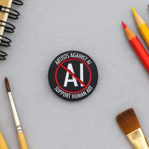 May include: A black circular button with the text "ARTISTS AGAINST AI" and "SUPPORT HUMAN ART" in white. The letters "AI" are crossed out with a red line. Art supplies, including pencils and paintbrushes, surround the button.