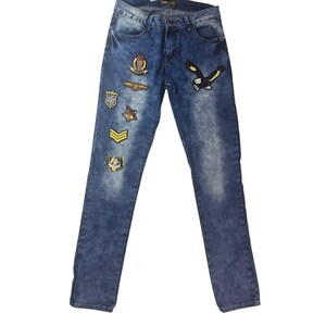 May include: Blue denim jeans with various embroidered patches, including an eagle, star, and military-style insignia. The jeans have a faded wash and a classic five-pocket design.