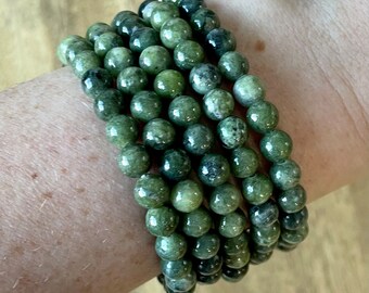 May include: A stack of green jade stone bracelets with a mottled pattern.