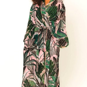 Puede incluir: Una larga bata de color rosa y verde con estampado floral y un cintur&oacute;n para atar. La bata tiene un ribete verde y mangas largas.