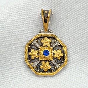 Octagonal silver and gold pendant featuring a central blue cubic zirconia surrounded by four rows of clear cubic zirconia and gold floral motifs